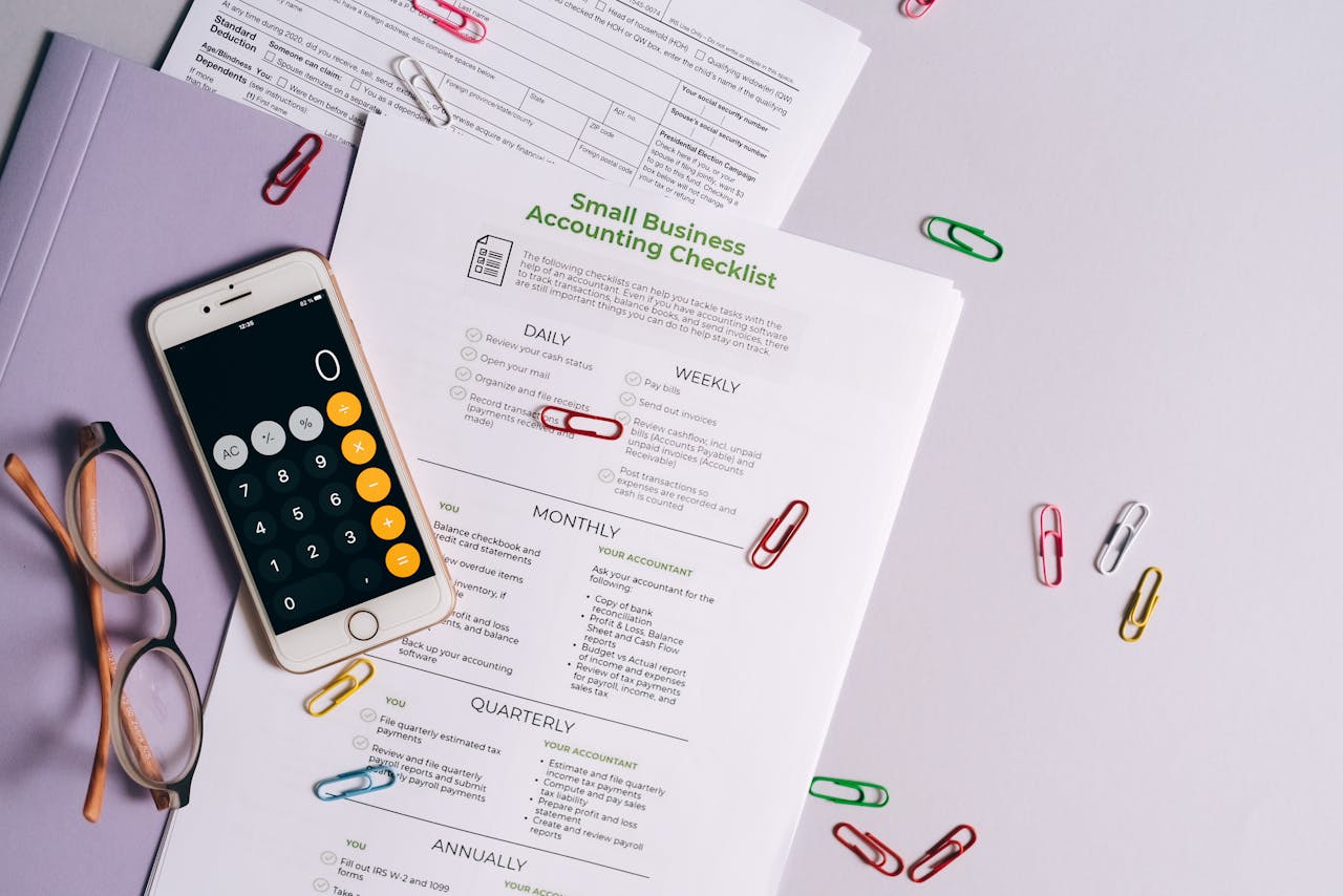 Top view of accounting essentials including smartphone, eyeglasses, and paperwork.
